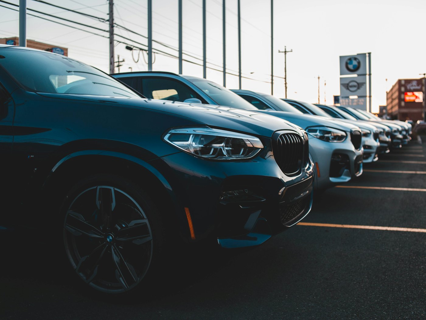 A row of cars lined up on a dealer forecourt, front three-quarter view