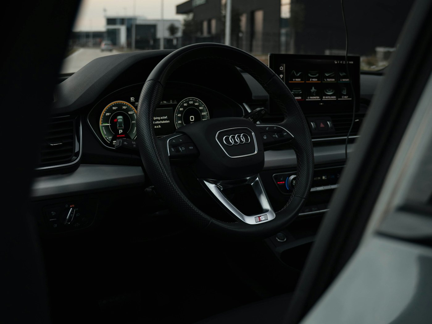 Car interior seen through the driver's window — steering wheel and instrument display